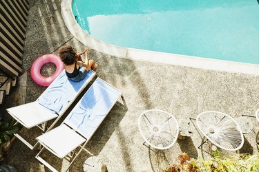 Overhead view of woman sitting on edge of lounge chair by pool
